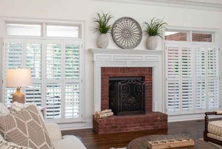 Two sets of plantation shutters set in between a brick fireplace.